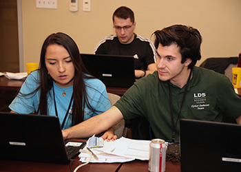 a young man and young woman work on laptops