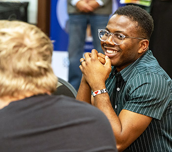 a divers crowd of RMCCDC competitors laugh and enjoy an expert presentation in a lecture hall on the Regis University campus 