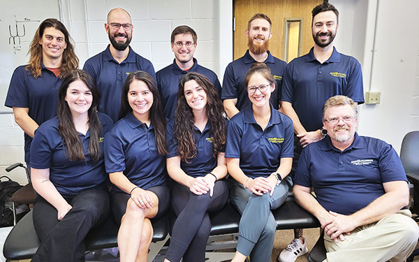 a cohort of Orthopaedic Physical Therapy Residency students and faculty smile for the camera in matching shirts in a classroom in Denver, Colorado