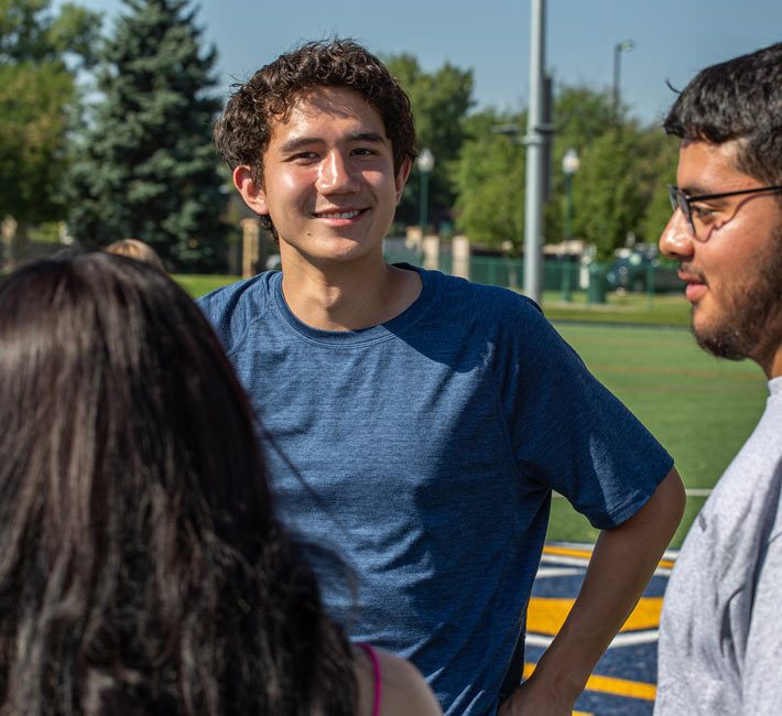 Three students stand on the Regis soccer field