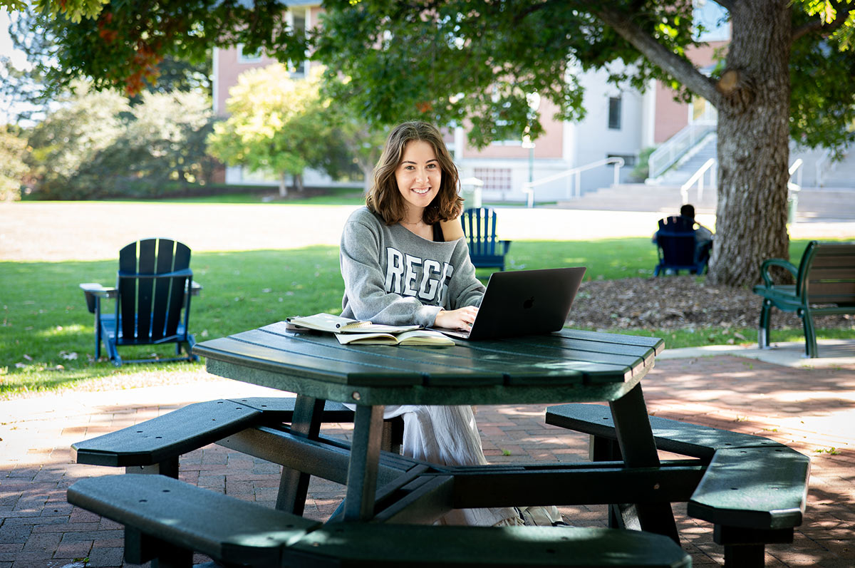 Rylie sits at a picnic table studying on the Quad at Regis University, the only Jesuit Catholic College in Colorado