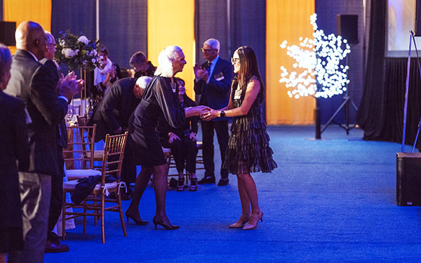 a student shakes hands with a professor at the evening Scholar Dinner series event