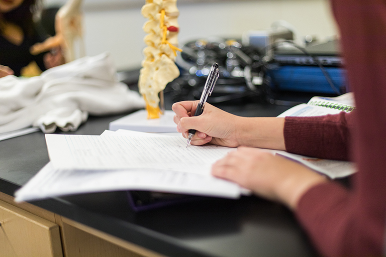 student writing in notebook in science lab