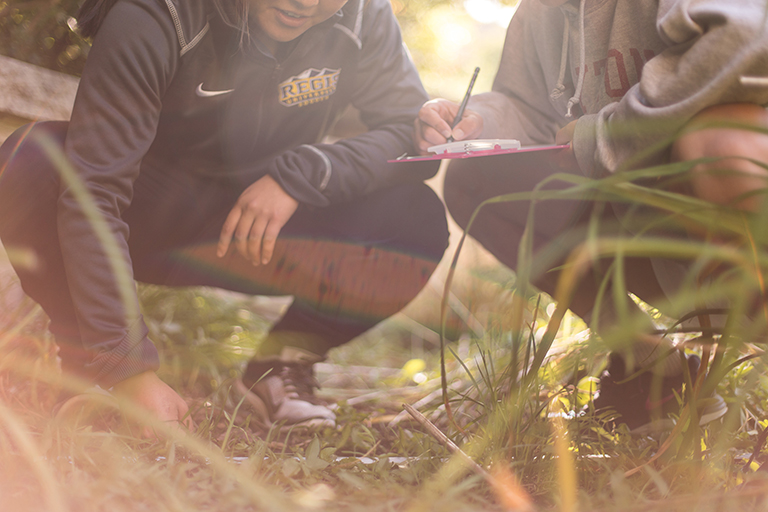 students examining soil and making notes on a clipboard