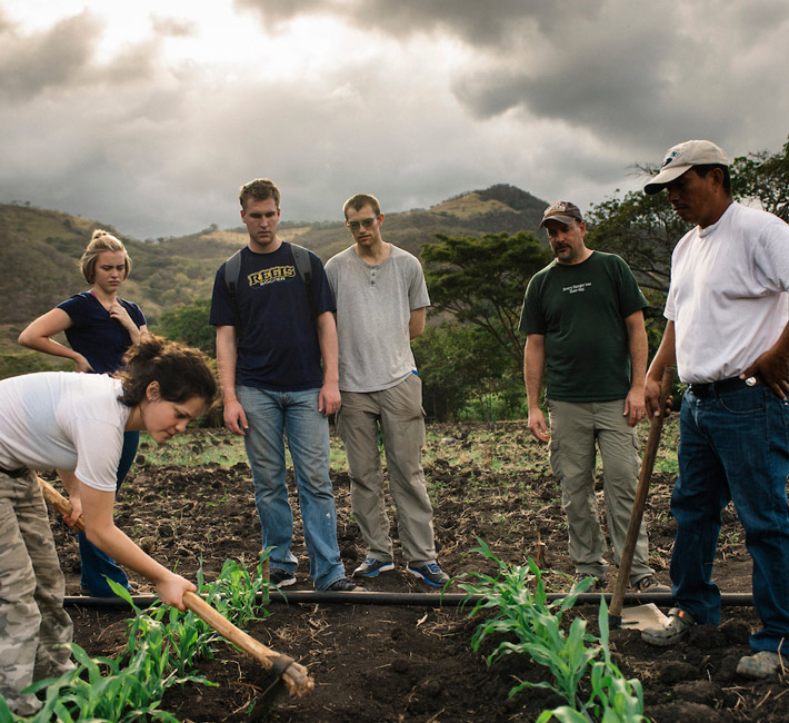 Students participating in a hands-on service project by planting crops with a local community.