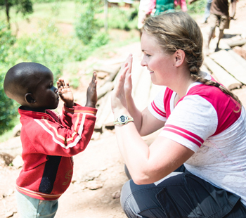 A SOFE student giving a high five to a young boy in Uganda.
