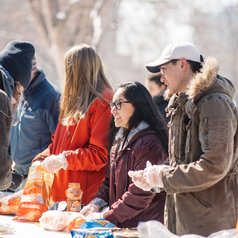 Students volunteering to serve food at a campus community event.