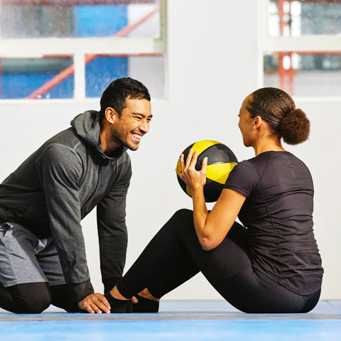 A Sports Physical Therapy student helps an athlete with an exercise outdoors