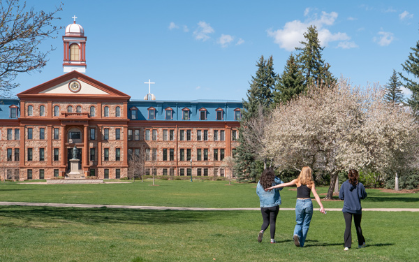 Three students walking across the common toward main hall