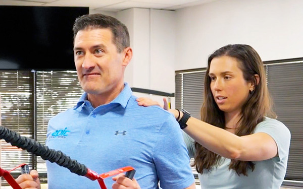 a Regis physical therapy student demonstrates on a faculty member how to do an exercise at the simulation center