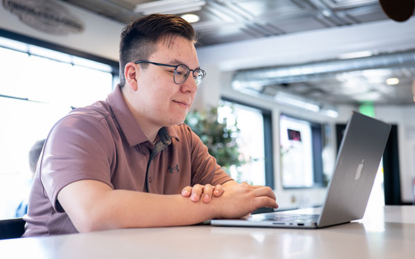 a Regis student enjoys the flexible hybrid format while studying online on a laptop in a cafe in Denver, Colorado
