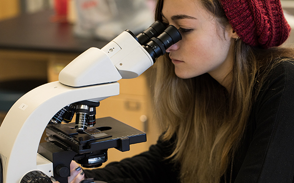 Woman looks in microscope in classroom