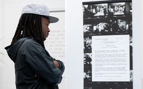 Student examining a display of historical photos and documents in an exhibit.
