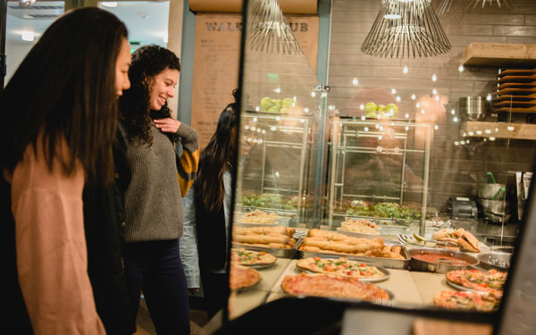 Students looking at a selection of pizzas deciding which to choose for lunch.