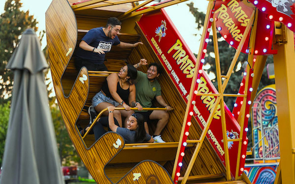 students smile and wave while riding the Pirate's Revenge carnival ride