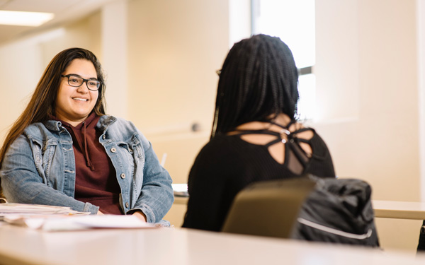 Regis University students having a conversation in a classroom.
