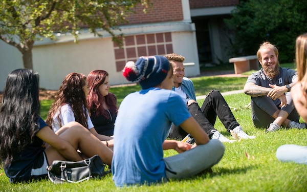 Students sit in a circle on the grass