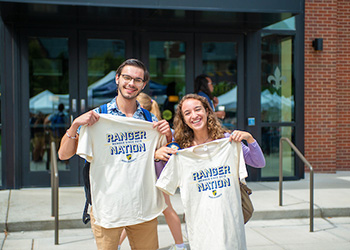 two students hold up their Ranger Nation t-shirts during Welcome Week on the Quad