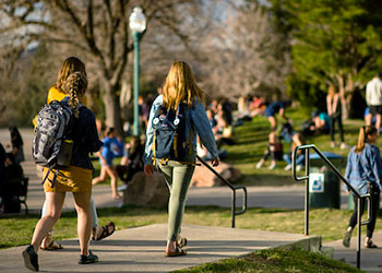 students wearing backpacks walk to class along the sidewalk outside Claver Hall on the northwest denver campus