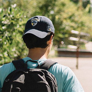 student wearing baseball cap walking outside