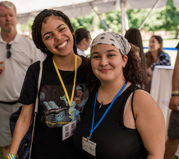 Two students underneath a canopy smile together