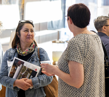 Two people at a Regis admissions event look at each other and interact