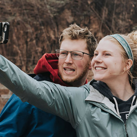 three students pose for a group selfie on an Outdoor Adventure Program trip to the Hoover Dam