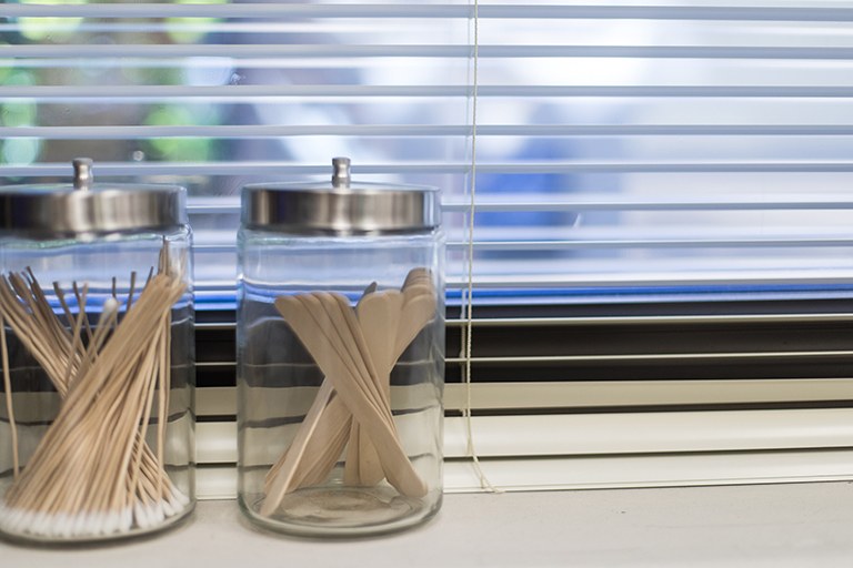 tongue depressors and cotton swabs in jars lined up on a counter