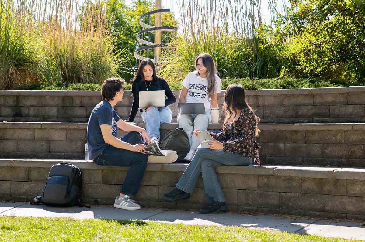 Students studying and collaborating together outdoors on Regis campus.