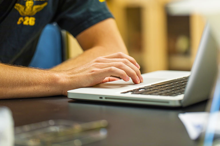 closeup of man's hands typing on a laptop