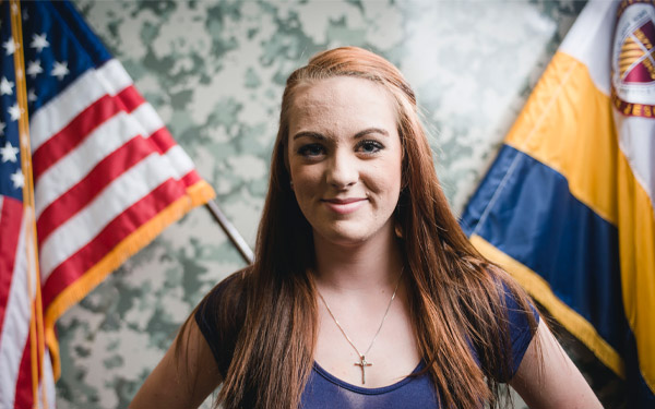 female veteran standing in front of the American flag