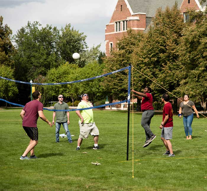students play a game of volleyball on the Quad on the Northwest Denver campus