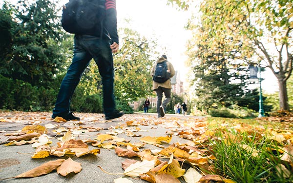 students walk through fall leaves