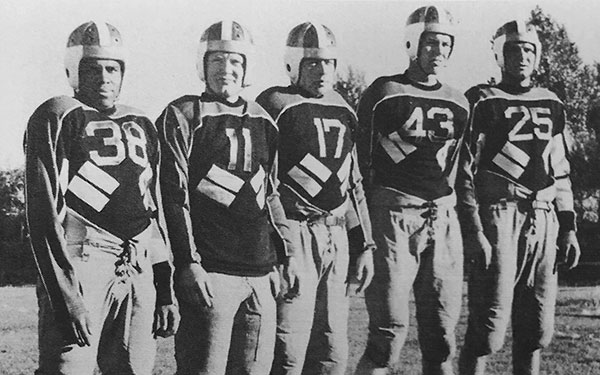 Walter Springs and 4 other men stand in a line wearing 1940s football uniforms