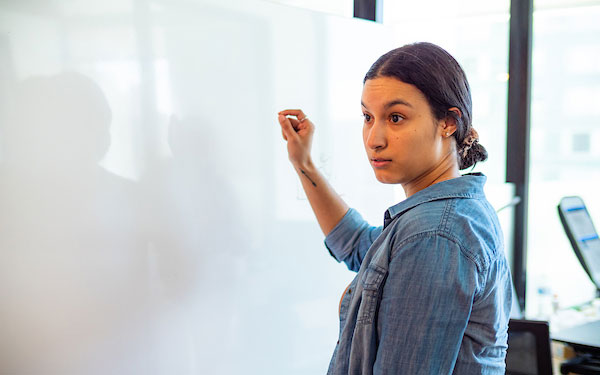 young woman writes on a white board