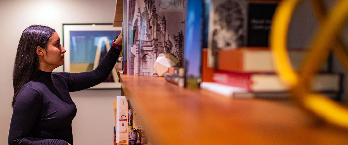 young woman browses books on a shelf