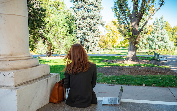 young professional woman works on a laptop in the park