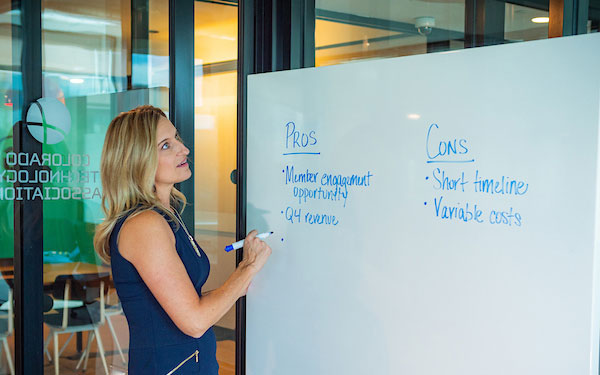 professional woman writes pro/con list on a whiteboard