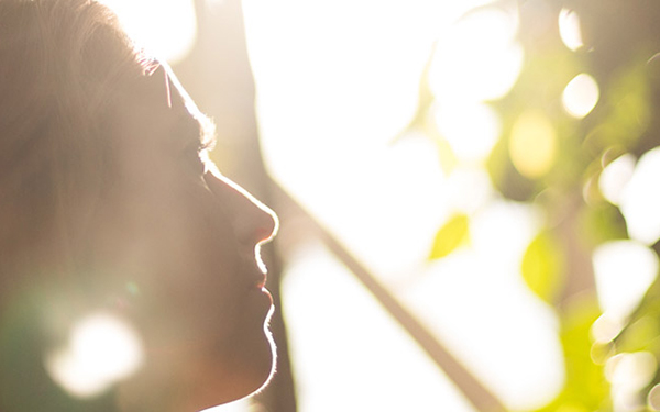 woman's face in silhouette, sunshine and trees