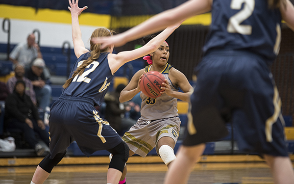 One player holding ball looking right while two opponents stand in front