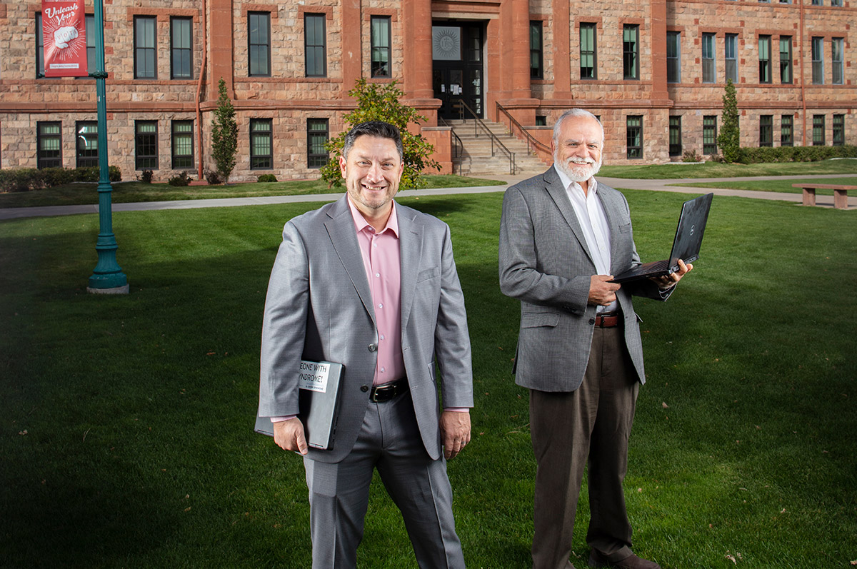 Higher Learning Partners employees Thomas Gilhooly and Adam Samhouri stand in front of Main Hall on the Northwest Denver Campus 
