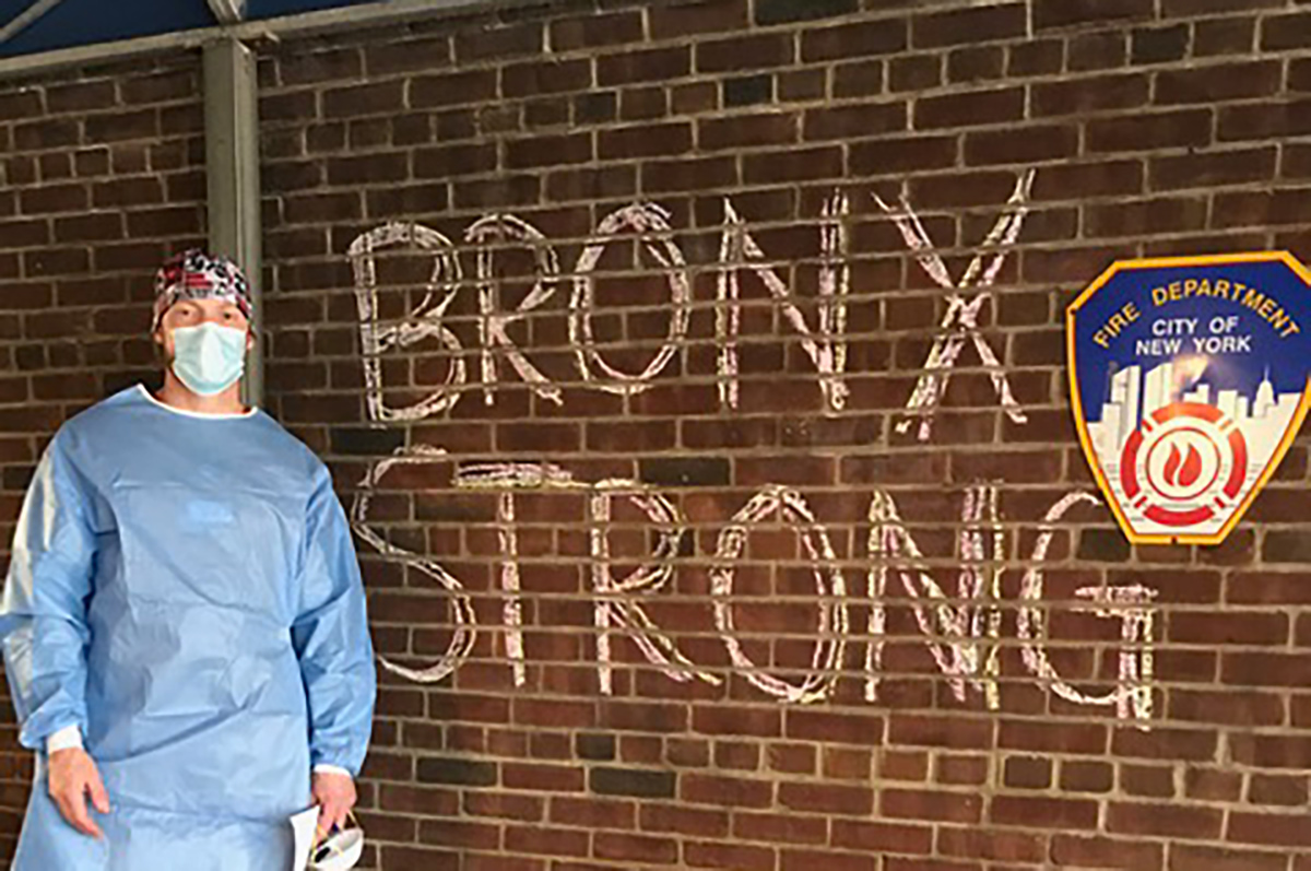 Alexander Herrmann stands in front of a mural that says the words "Bronx Strong"