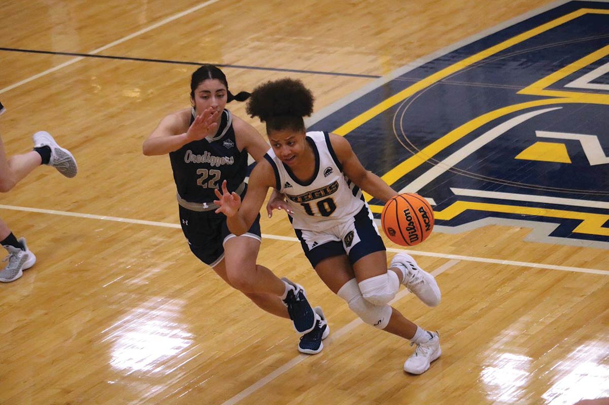 A Regis player charges with the ball while an opponent covers in the Regis University Fieldhouse on the Northwest Denver campus.