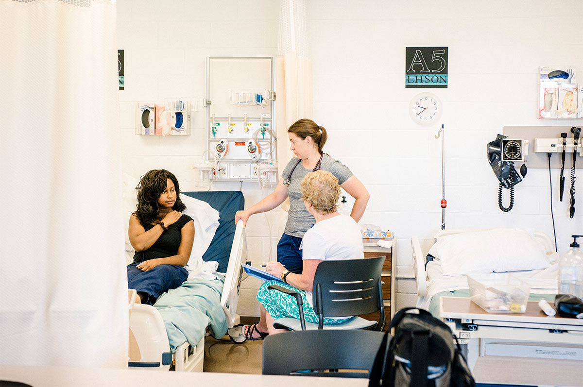 Nursing student and faculty speak with patient during clinicals