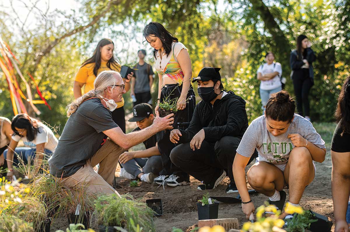 Prof. Jason Taylor and first-year students plant a garden with potted plants 
