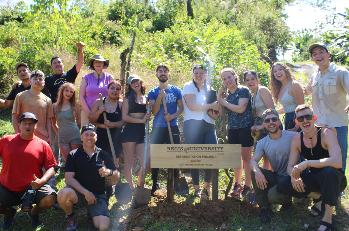 students smile in front of a sign for the Costa Rica reforestation project