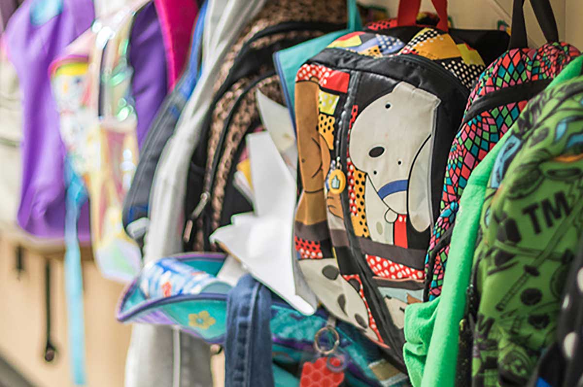 backpacks hanging on a rack at a school