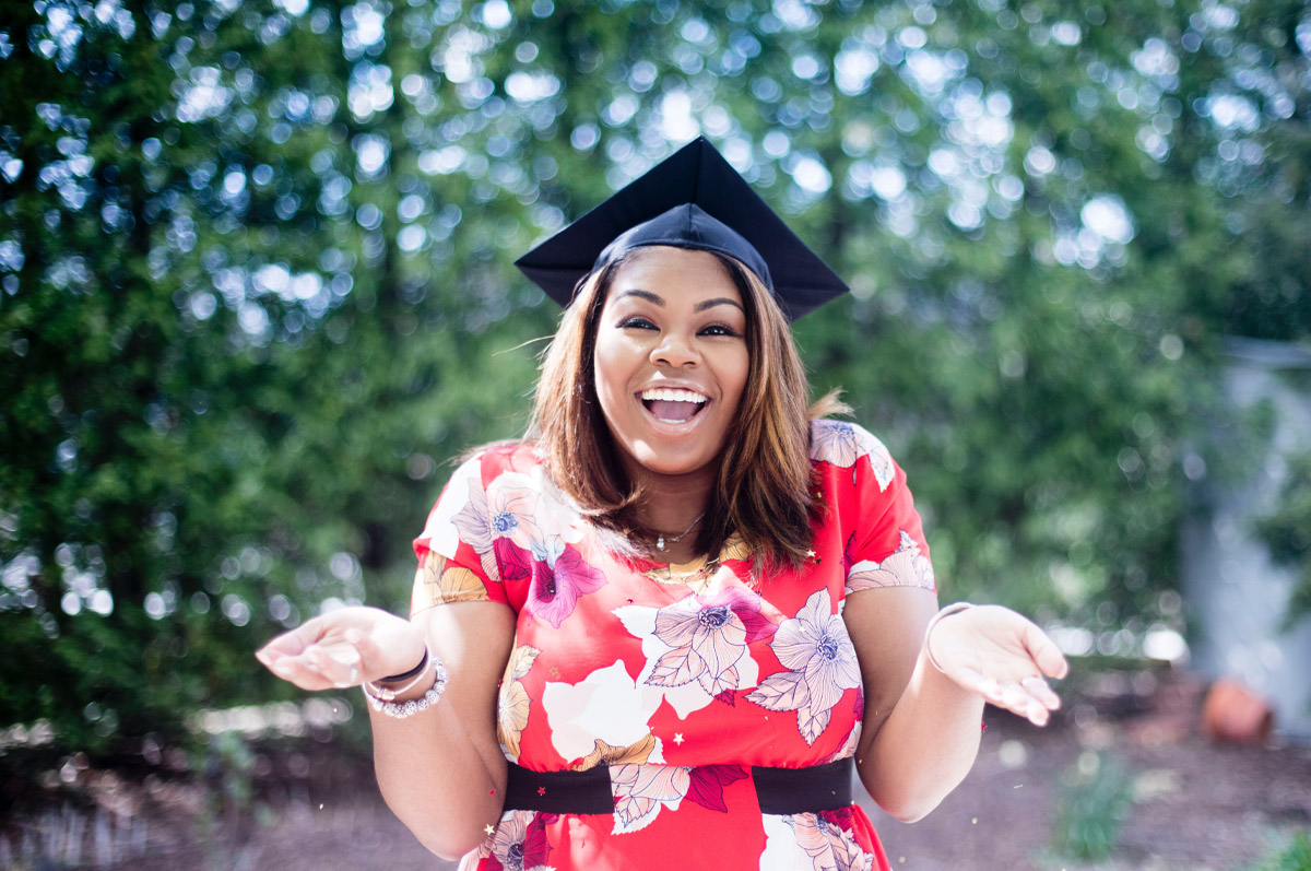 woman with graduation cap shrugs with smile