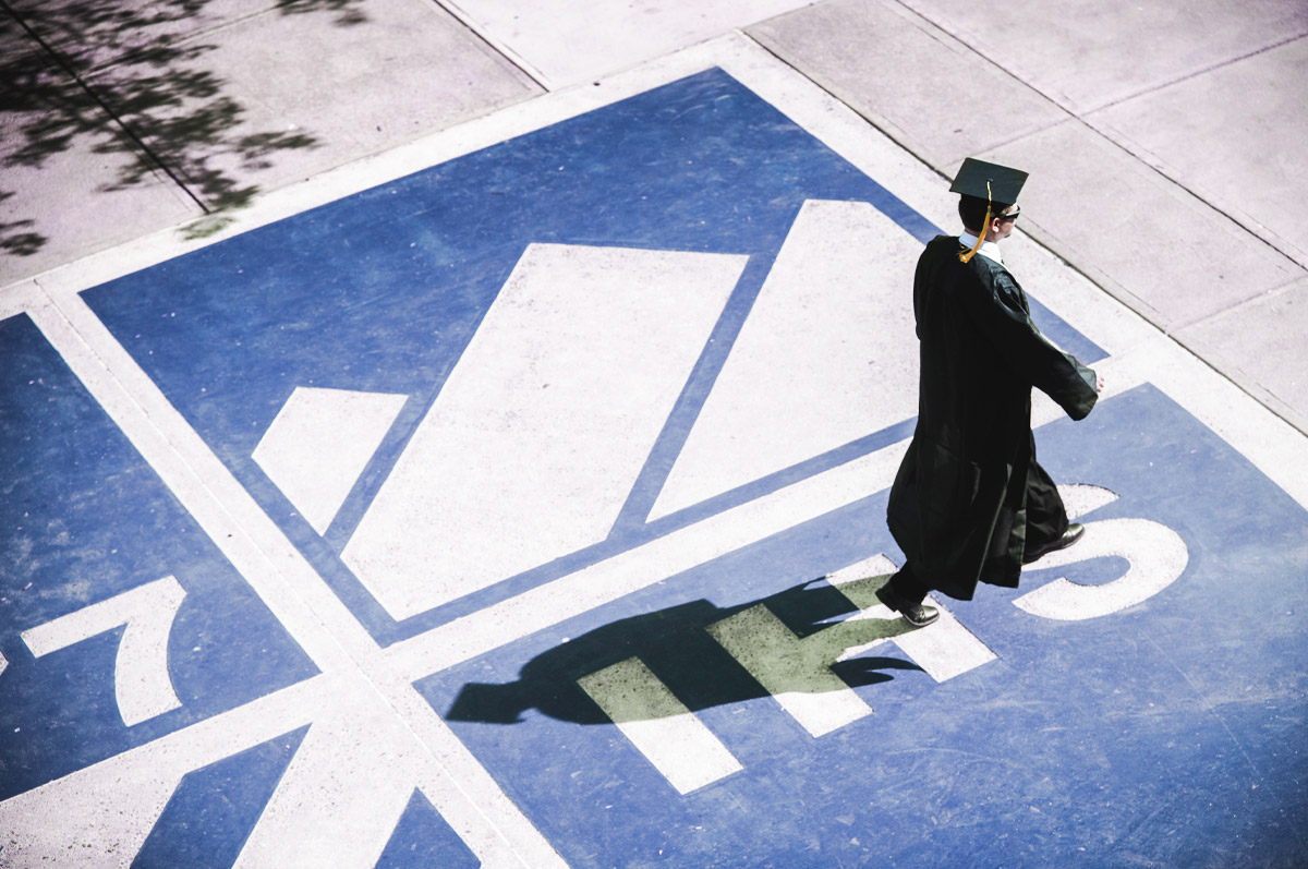 jesuit graduate walking across regis shield