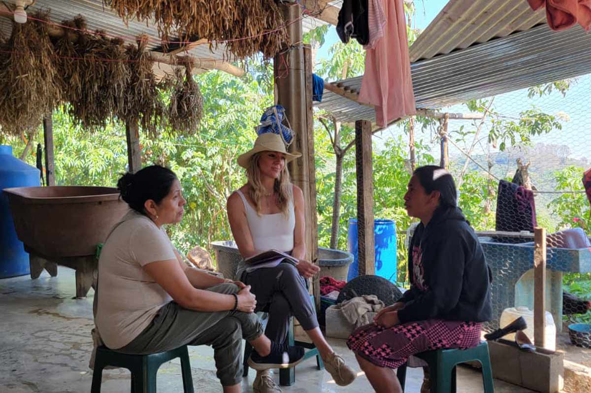 Heidi Johnson sits with two other individuals underneath a shelter with open walls